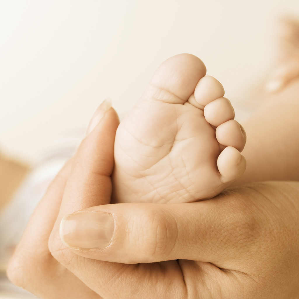 Close up of baby's foot in mother's hand --- Image by © Royalty-Free/Corbis